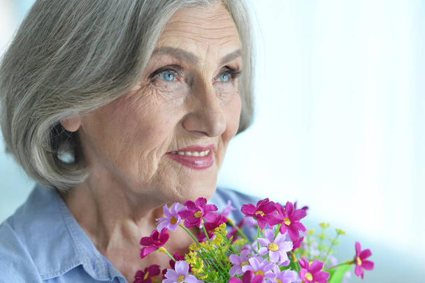 portrait of happy senior woman at home with flowers  - Zdjęcie, obraz
