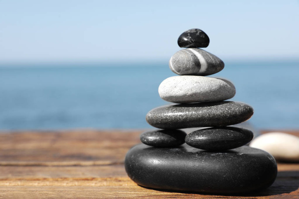 Stack of stones on wooden pier near sea seascape, space for text. Zen concept - Foto, Imagen