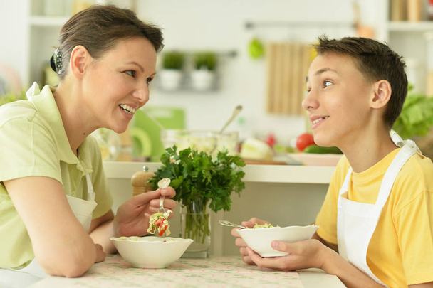 Mother and son eating fresh salad at kitchen - Foto, Imagen