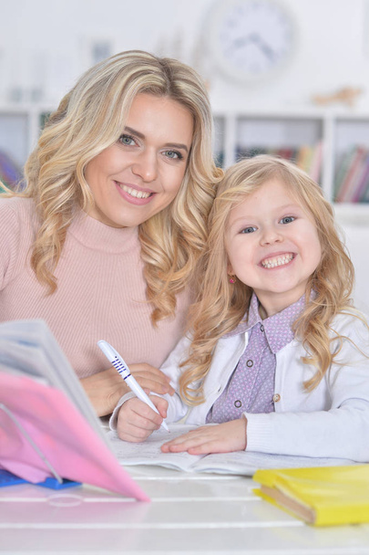 Portrait of a beautiful little cute girl  with mother doing homework  - Fotó, kép