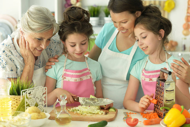 gelukkige familie heerlijke verse salade in de keuken - Foto, afbeelding