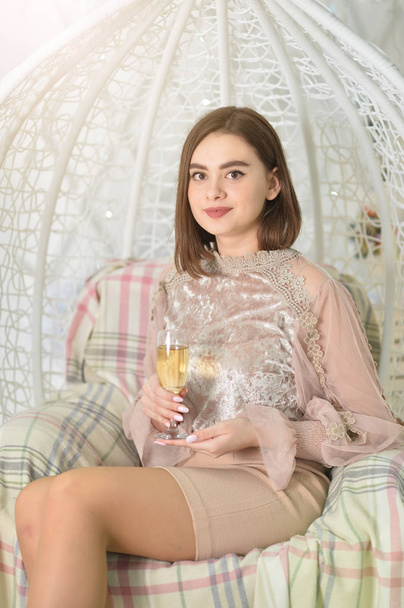 Beautiful young woman posing on swing with champagne  - Foto, afbeelding