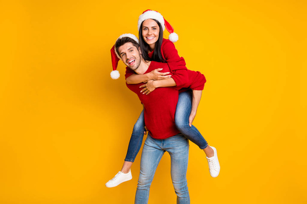 Portrait of cheerful man hug his sweethearts piggyback wear red sweater denim jeans isolated over vivid color background - 写真・画像