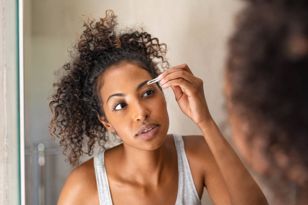 African woman plucking eyebrows - 写真・画像