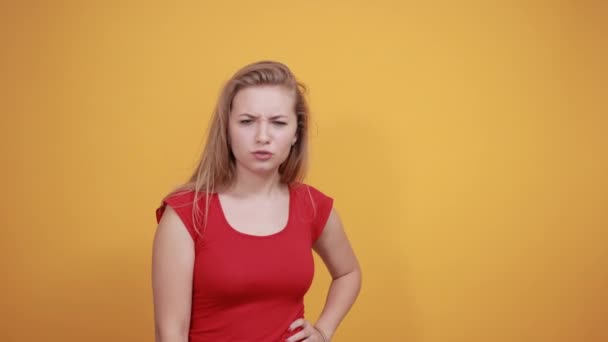 молода блондинка в червоній футболці над ізольованим помаранчевим тлом показує емоції
 - Кадри, відео