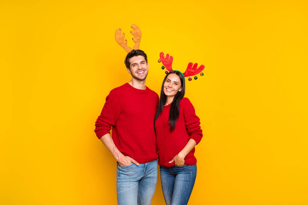 Portrait of two lovely people romantic couple hug enjoy wear elk horns mask red pullover denim jeans isolated over yellow background - Foto, immagini