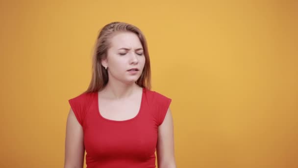young blonde girl in red t-shirt over isolated orange background shows emotions - Footage, Video