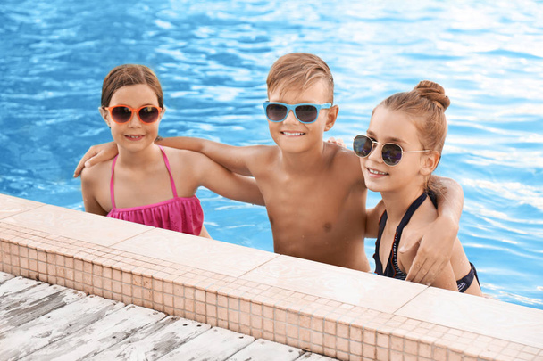 Happy children in swimming pool on sunny day - Foto, afbeelding
