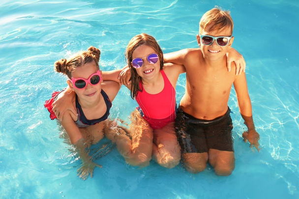Happy children with sunglasses in swimming pool - Foto, afbeelding