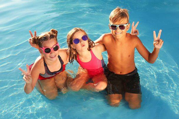 Happy children with sunglasses in swimming pool - Photo, Image
