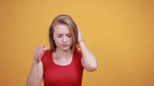 Młoda blond dziewczyna w czerwonym t-shirt na białym tle pomarańczowe pokazuje emocje - Materiał filmowy, wideo