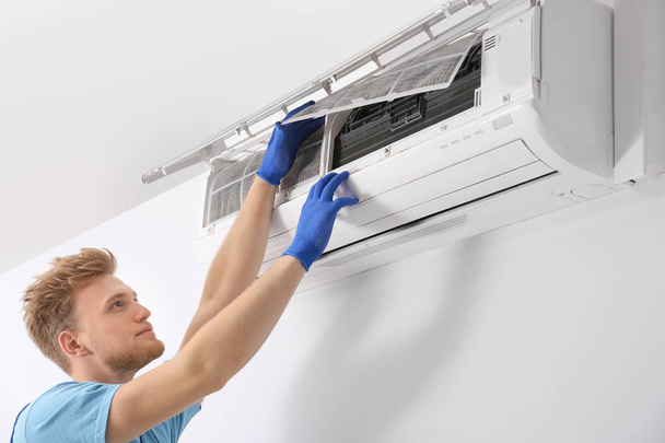 Professional technician maintaining modern air conditioner indoors - Foto, Imagem