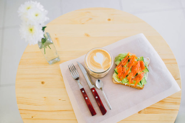Overview of a coffee and sandwich waiting on a wooden table. - Foto, imagen