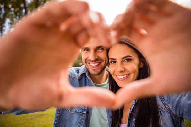 Close-up portrait of his he her she nice attractive cheerful tender winsome amorous married spouses tourists showing heart frame shape perfect match in green wood forest - Фото, изображение