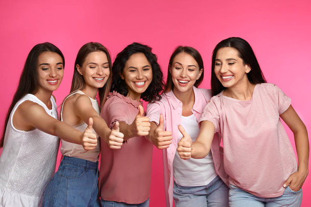 Happy women showing thumbs up on pink background. Girl power concept - Фото, зображення