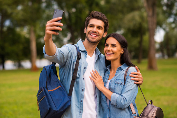 Photo of millennial pair using telephone making selfies going green park wear casual denim outfit - Φωτογραφία, εικόνα