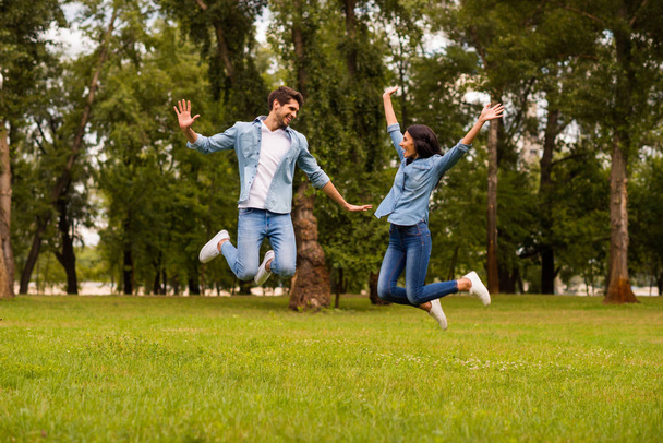 Full size photo of overjoyed pair jumping high in green park best weekend ever wear denim outfit - Valokuva, kuva