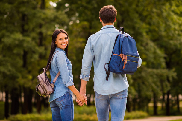 Behind view photo of cute pair groupmates walking dormitory hostel after lessons hold arms wear denim outfit - Фото, изображение