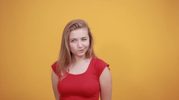 Młoda blond dziewczyna w czerwonym t-shirt na białym tle pomarańczowe pokazuje emocje - Materiał filmowy, wideo