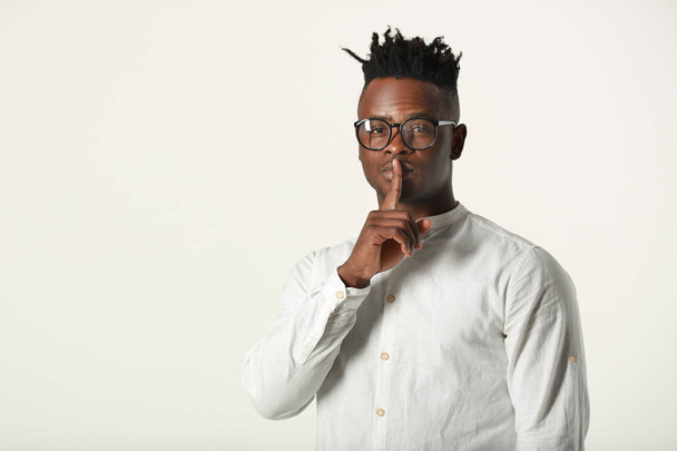 handsome young african man in glasses and white shirt on white background with hand gesture - Zdjęcie, obraz