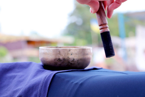 Музыкальный инструмент - пение Гималайской чаши. Поющий колокол держит девушку в руке. Практика целительных вибраций, сурия, йога, медитация
 - Фото, изображение