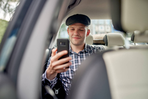 Photo of man with phone in his hands driving car. - 写真・画像
