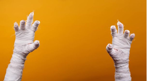 Photo of two mummy hands on empty orange background . - Zdjęcie, obraz