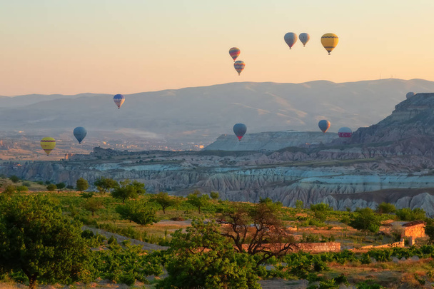Interessant rotsachtig terrein en veel luchtige veelkleurige ballen in de lucht. Turkije. Cappadocië. - Foto, afbeelding