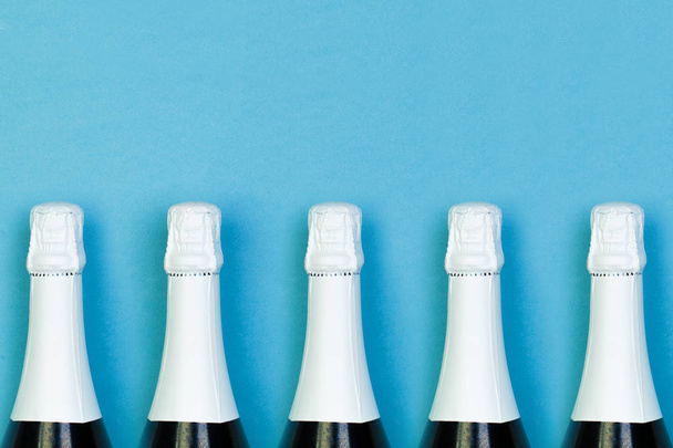 Μπουκάλι αφρώδους κρασιού στη σειρά σε μπλε φόντο. Γιορτές, πάρτι - Φωτογραφία, εικόνα