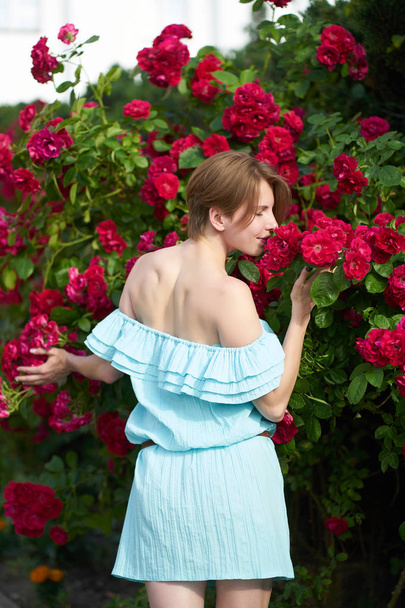 Sensual redhead girl wearing stylish blue light dress smelling b - Photo, Image