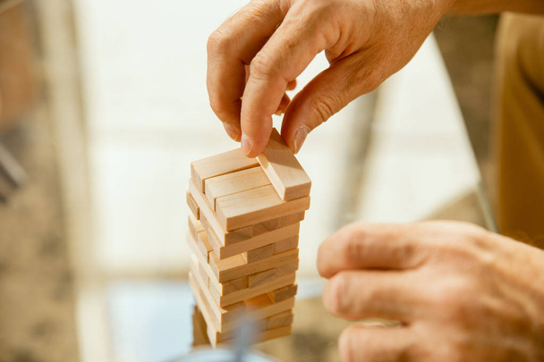 Primer plano de las manos de los hombres mayores haciendo su constructor de madera en casa - concepto de estudio en casa
 - Foto, Imagen