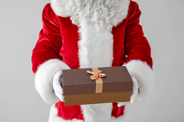 Santa Claus with gift on light background, closeup - Photo, Image