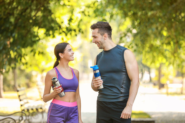 Спортивная молодая пара с бутылками воды в парке
 - Фото, изображение