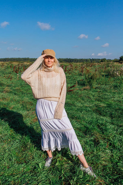 Happy beautiful blond woman walking in a green field - Valokuva, kuva