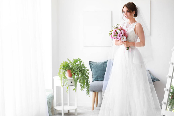 Beautiful young bride with bouquet before wedding ceremony at home - Photo, image