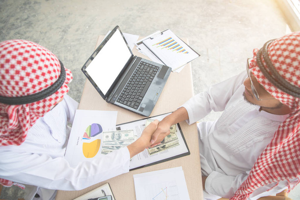 アラブのサウジアラビアのビジネスマンは、ビジネスの背景として使用して成功した取引のために手を振る(成功と達成の概念) - 写真・画像