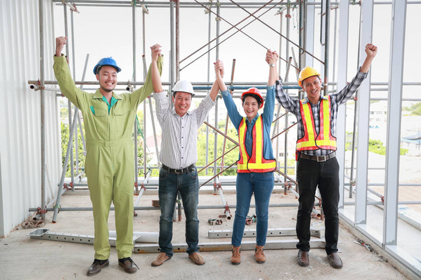 建設現場で成功したプロジェクトを終えた後、ポートレートエンジニアの人々は手を挙げる - 写真・画像