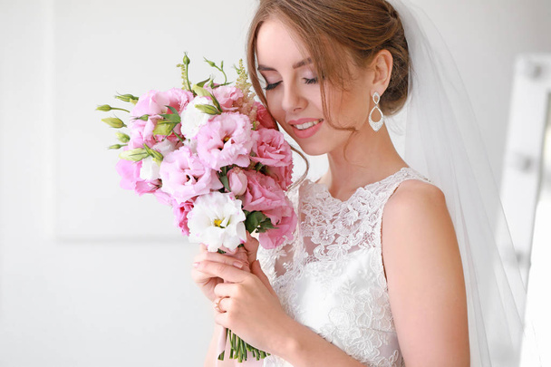 Beautiful young bride with bouquet before wedding ceremony at home - Фото, изображение