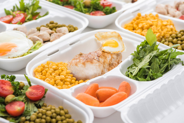 selectieve focus van eco pakket met arugula, groenten en vlees op witte achtergrond  - Foto, afbeelding