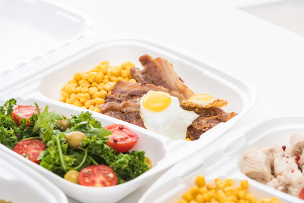 вибірковий фокус екологічного пакету з кукурудзою, м'ясом, смаженим яйцем та салатом на білому тлі
  - Фото, зображення