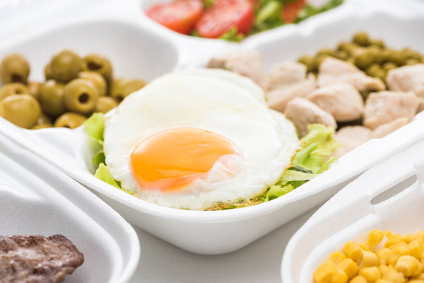 selective focus of eco package with vegetables, meat, fried egg and salad on white background  - Photo, Image