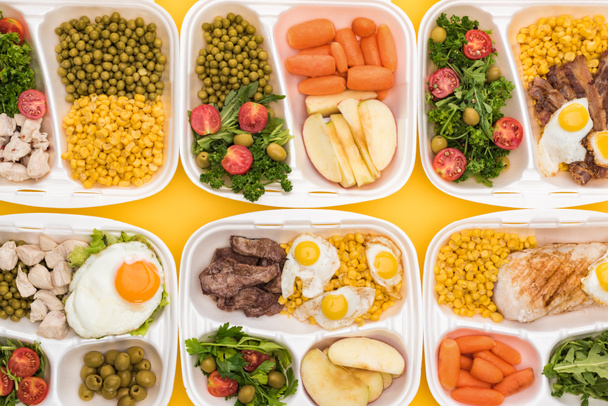 vista superior de los paquetes ecológicos con manzanas, verduras, carne, huevos fritos y ensaladas aisladas en amarillo
  - Foto, Imagen