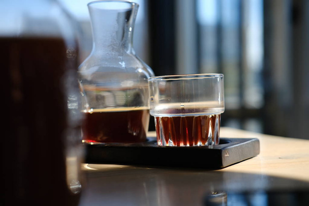 jug and glass of fresh cold brewed black coffee on cafe table - Фото, изображение