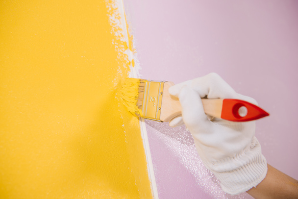 vista parcial de la pared de pintura de pintor en amarillo y rosa con pincel
 - Foto, Imagen
