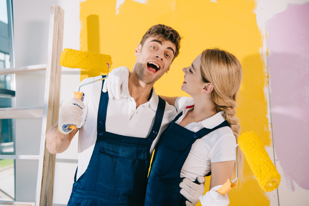 cheerful painter looking at camera while standing near attractive colleague - Fotoğraf, Görsel