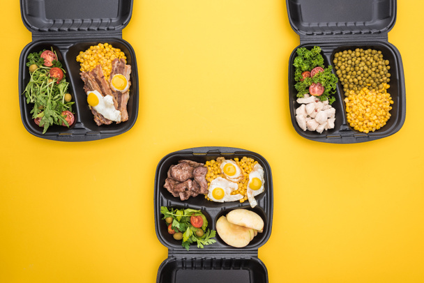 vista superior de pacotes ecológicos com maçãs, legumes, carne, ovos fritos e saladas isoladas em amarelo
  - Foto, Imagem