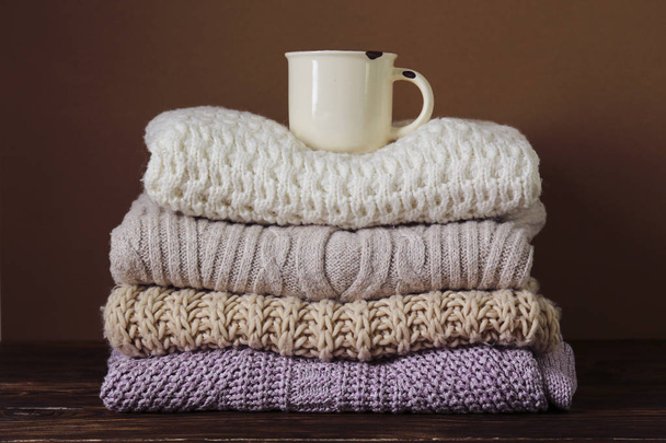Pile of knitted sweaters of different colors and patterns perfectly stacked. - Фото, зображення