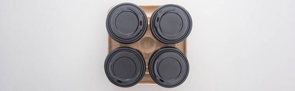 panoramic shot of paper cups with coffee in cardboard tray on white background  - Foto, afbeelding