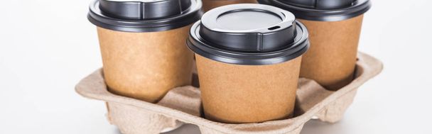 Panoramaaufnahme von Pappbechern mit Kaffee in Papptablett auf weißem Hintergrund  - Foto, Bild