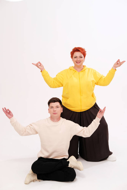 studio portrait of funny couple posing with raised arms on plain background - Foto, imagen